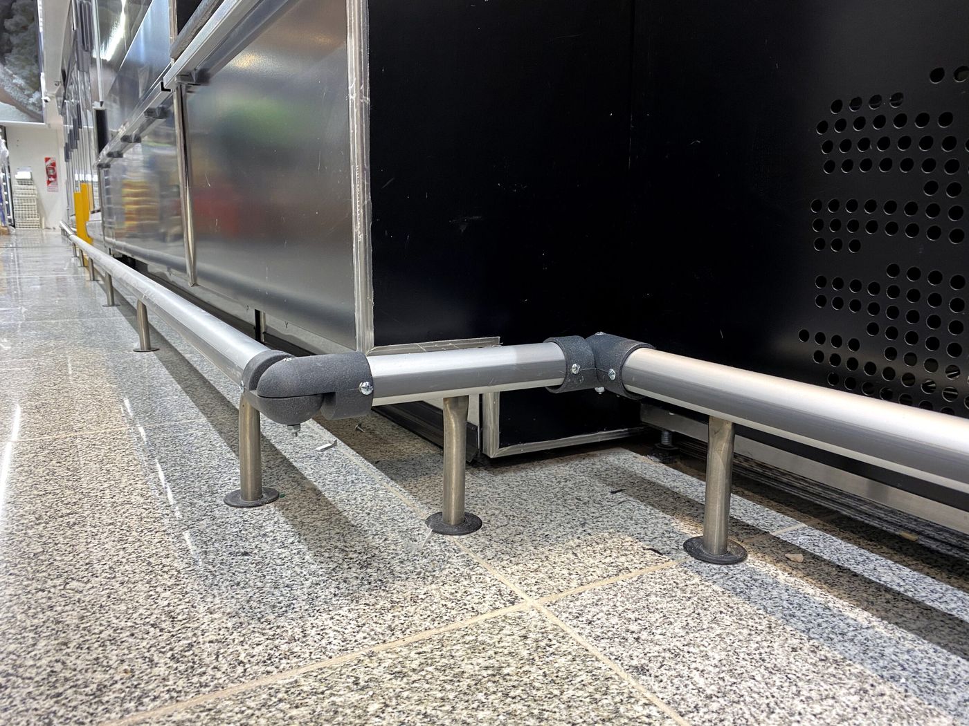 Esquina de una defensa de acero inoxidable junto a una heladera