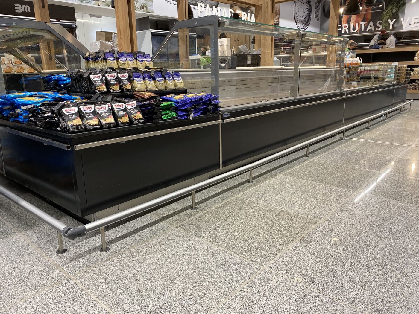 Defensa de acero inoxidable frente a un exhibidor refrigerado